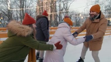 Üç kişilik mutlu bir ailenin kış akşamı gün batımında buz pateni düzeninde el kamerasıyla çekilmiş görüntüleri.