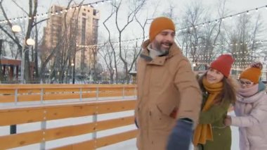 Üç kişilik bir ailenin kış akşamı buz pateni pisti boyunca tren formasyonunda ağır çekim görüntülerini izliyoruz.