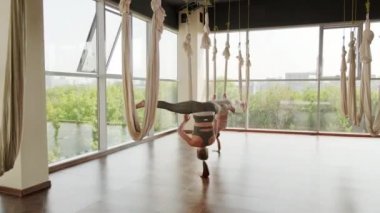 Stüdyoda yoga yapan genç kadınların çekimleri. İpek hamaklarda sallanarak ters poz veriyorlar.