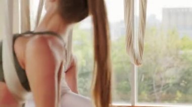 Sıkı spor giyim giymiş iki enerjik beyaz kadının el kamerasıyla el ele tutuşup el ele tutuşarak hamaklarda dönmelerini gösteren görüntüler.