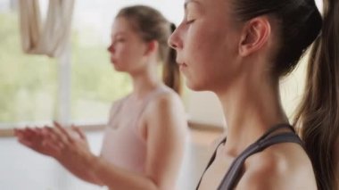 Yoga stüdyosunda meditasyon yapmak için dua pozisyonu alan kadın elleri yavaş çekimde aşağı doğru eğiliyor.