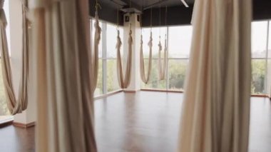 Her yerde ipek hamaklar ve güzel yaz manzaralı panoramik pencereleri olan boş geniş bir aero yoga stüdyosunun yakınlaştırılmış görüntüleri.