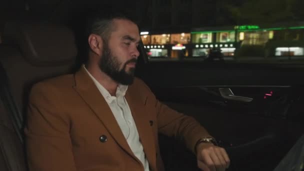 재킷을 잘생긴 사업가의 야간비싼 뒷좌석에 자신의 시계에 시간을 — 비디오