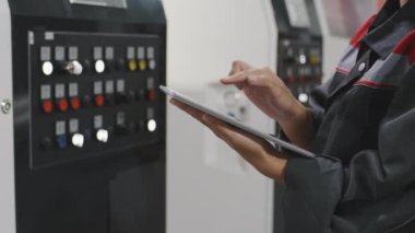 Makineler için dijital tablet ayarlama parametreleri kullanarak tanınmayan kadın fabrika işçisinin orta bölüm yavaş çekim yakın çekimi.