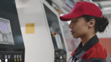Modern makine ekipmanları için parametreleri ayarlarken dijital tablet kullanan kadın karışık ırk fabrika işçisinin yavaş çekimde yakınlaştırılması