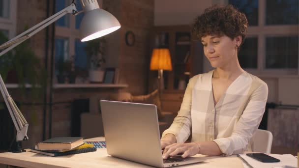 Tiro Médio Jovem Sentada Mesa Casa Digitando Laptop Seguida Sorrindo — Vídeo de Stock