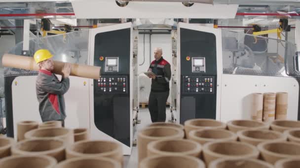 卷绕聚乙烯用螺旋纸板管生产中穿着工作服工人的慢动作介质镜头 — 图库视频影像