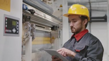 Polietilen film üreten makine ekipmanları için dijital tablet ayarlama parametreleri üzerinde çalışan erkek mühendisin orta yavaş çekimleri