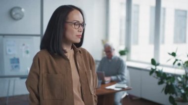 Ofiste kollarını kavuşturup kameraya bakan, kendine güvenen, gözlüklü genç bir kadının belindeki portre görüntülerini göster.