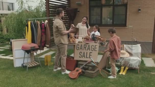 Adamın Oğlunun Garaj Satışındaki Eşyalara Bakarken Neşeli Kadın Kızla Sohbet — Stok video