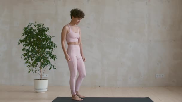 穿着粉色运动服的年轻女子在瑜伽垫上做三角姿势的慢镜头 — 图库视频影像