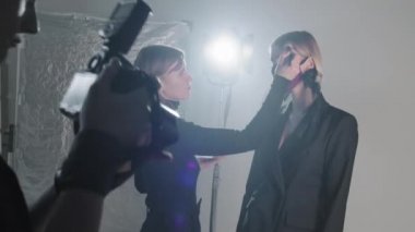 Erkek fotoğrafçı fotoğraf makinesine bakarken kadının yüz maskesi takan kadın modelinin yavaş çekimleri.