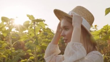 Güneş ışığı altında kırsal kesimlerde kameraya poz veren beyaz şapkalı güzel bir kadının yavaş yavaş yakın plan portresi.