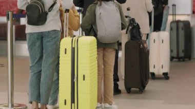 Yavaş çekimde, bavulları olan, giriş sırasında bekleyen ve uçuş için kayıt yaptıran insanların videoları.