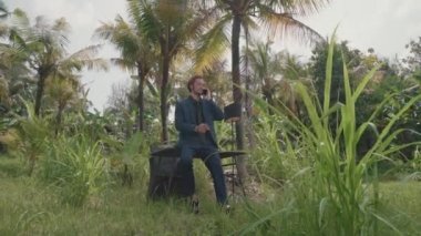 İş gezisinde palmiye ağaçlarının arasında dikilirken başarılı bir iş adamının telefon konuşması.