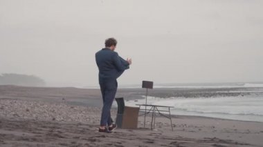 İş ortağıyla telefonda konuşurken boş kıyı şeridinde yürüyen yakışıklı bir iş adamı.