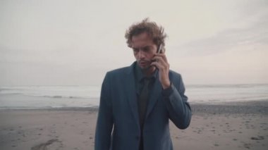 İnsansız hava aracı, yakışıklı iş adamının Bali 'de ıssız bir plajda telefon görüşmesi yaparken görüntülerini çekiyor.