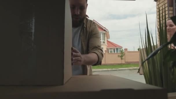 从后备箱开枪射击 快乐的胡子男子和年轻女子在搬家时包装纸板箱 — 图库视频影像