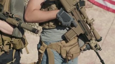 Kamuflaj giysileri ve güneş gözlüklü genç Amerikan piyade subaylarının arka planda Amerikan bayrağıyla kırsalda duran keskin nişancı tüfekleri ile çekilmiş fotoğrafları.