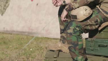 Kamuflaj üniformalı acımasız Amerikan subayının dışarıda ordu davalarının üzerinde sigara içerken çekilmiş görüntüleri.