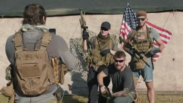 米軍の若い兵士たちが 米軍旗を背景にカメラのポーズをとって写真を撮る中撮影 — ストック動画