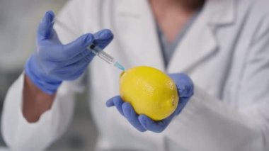 Laboratuvarda genetik olarak modifiye edilmiş limona yapay C vitamini enjekte eden tanınmayan teknoloji uzmanını kapatın.