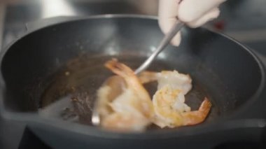 Lokanta mutfağındaki düdüklü tencerede kaplan karidesleri pişiren tanınmayan şefin yavaş yavaş yaklaşması.