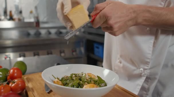 アルグラ チェリートマトとおいしいヘルシーなサラダに高品質のパルメザンチーズをトッピングした 知名度の低いシェフのスローモーションのクローズアップ — ストック動画