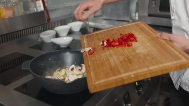 Yavaş çekimde taze dolmalık biber, soğan, mantar ve kabak kızartması restoranın mutfağında tavada kızartılıyor.