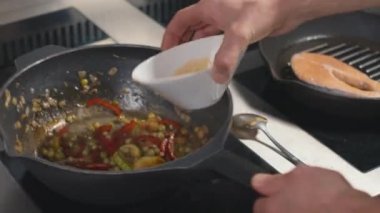 Yavaş çekimde şefin tavaya biraz sos ve kızarmış sebze eklemesi.