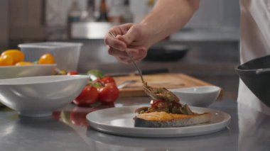 Restaurant mutfağında servis edilen somon bifteğine Asya usulü sebze ekleyen tanınmamış şefe yakın çekim.