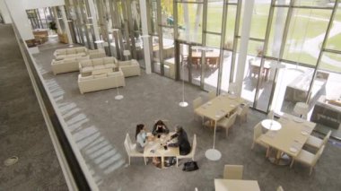 Modern restoranda masada oturmuş iş hakkında konuşan çok ırklı iş arkadaşlarının yukarıdan çekilmiş görüntüleri.