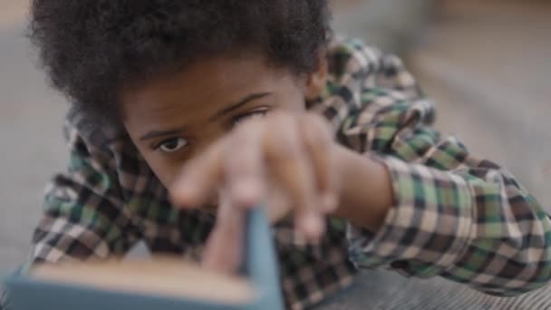 Långsam Närbild Söt Liten Afrikansk Pojke Läser Bok När Ligger — Stockvideo