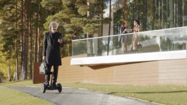 Yetişkin bir adamın gün ışığında jiroskop sürerken akıllı telefon kullandığı orta ölçekli görüntüler.