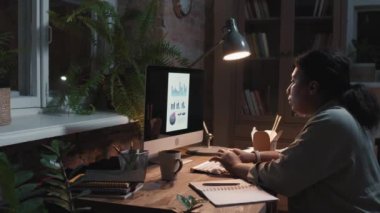 Afrika kökenli Amerikalı kadın bir ofis çalışanının gece vakti teslim tarihinden önce bilgisayarın karşısında tek başına oturup rapor verirken yan çekimler yavaş çekimde belden yukarı çekiliyor.