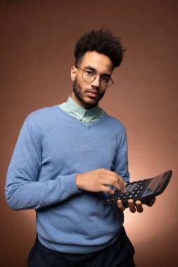 Gözlüklü, ciddi bir melez muhasebeci ve kameranın önünde dikilip hesap makinesinin tuşlarına basan şık bir gündelik kıyafet.