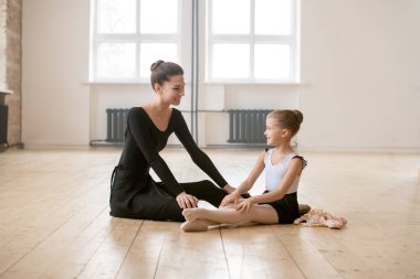 Küçük balerin yerde oturup bale öğretmeniyle konuşuyor. Eğitimden sonra dinleniyorlar.