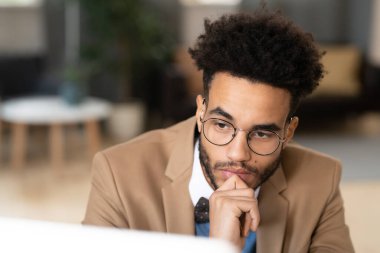 Gözlüklü dalgın işadamının ofisteki bilgisayar ekranına baktığı yakın plan fotoğraf.
