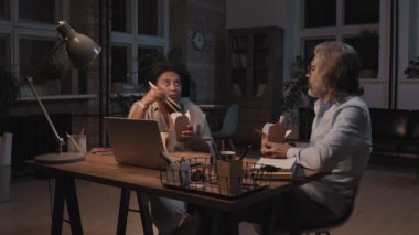 Muhtelif meslektaşların geç saatlere kadar ofiste kalıp, karton kutulardan tava yerken sohbet ettikleri orta boy bir fotoğraf.