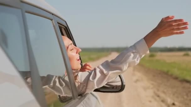阳光明媚的夏日 一个有着一头长长的卷发的快乐的年轻女子从车窗伸出胳膊的慢镜头 — 图库视频影像