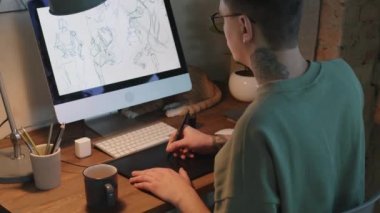 Profesyonel dövmeli grafik tasarımcısının el bilgisayarı yavaş çekimde yakın plan çizimi Stylus 'u kullanarak, bilgisayar monitörüne bakarak, karantina sırasında evden çalışarak