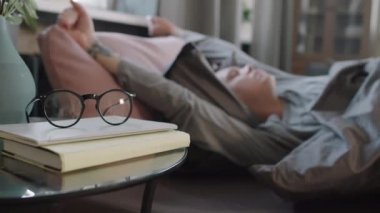 Kafkasyalı, dövmeli, uyanan, yatakta uzanan ve gözlüğünü takan yetişkin bir adam.