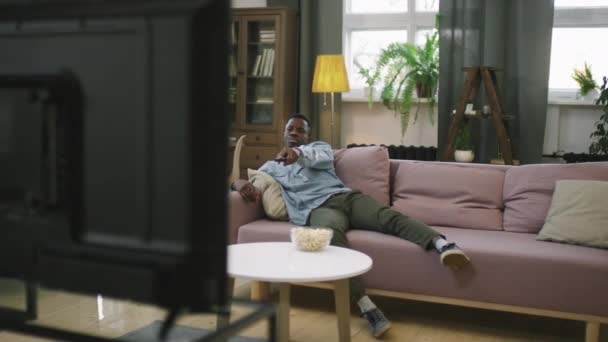 Panorámica Completa Hombre Afroamericano Joven Cambiando Canales Televisión Luego Encontrar — Vídeos de Stock