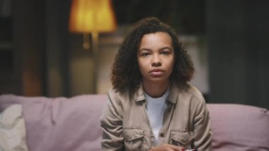 Şok olmuş afro kızın gece TV 'de heyecanlı bir film izlerken, oturma odasındaki kanepede otururken, yavaş çekimde belini kaldır.