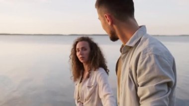 Güzel bir çiftin göl kıyısında el ele yürürken çekilmiş orta boy portresi.