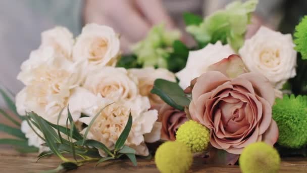花の店で木製のテーブルの上に横たわる新鮮な選んだ花の近くにパンニング 美しい花束でそれらを配置しながら プロの花 — ストック動画