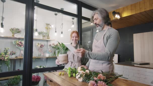 Medium Skott Blomsterhandlare Chattar Samtidigt Arrangera Färska Blommor Som Ligger — Stockvideo