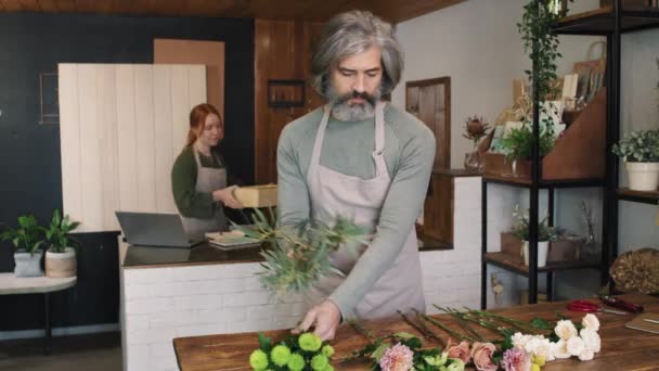Medium Porträtt Kaukasisk Vuxen Man Florist Sortera Nyplockade Blommor Träbord — Stockvideo