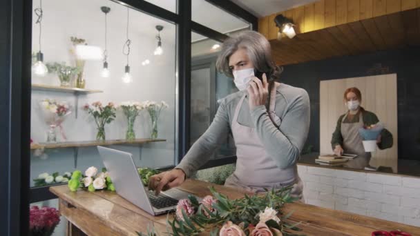 Tiro Médio Florista Masculino Adulto Usando Máscara Protetora Conversando Telefone — Vídeo de Stock