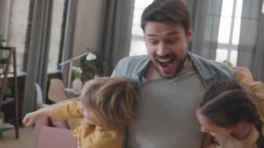 İki neşeli çocuğun mutlu babalarının, evde el ele gezip eğlenirken çekilmiş yavaş çekim orta ölçekli görüntüleri.